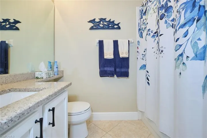 Bathroom with toilet, vanity, tile patterned floors, and curtained shower