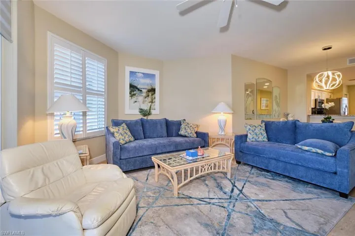 Living room featuring ceiling fan with notable chandelier