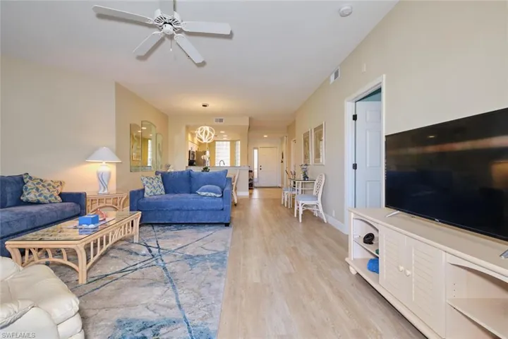 Living room featuring ceiling fan with notable chandelier and light hardwood / wood-style floors