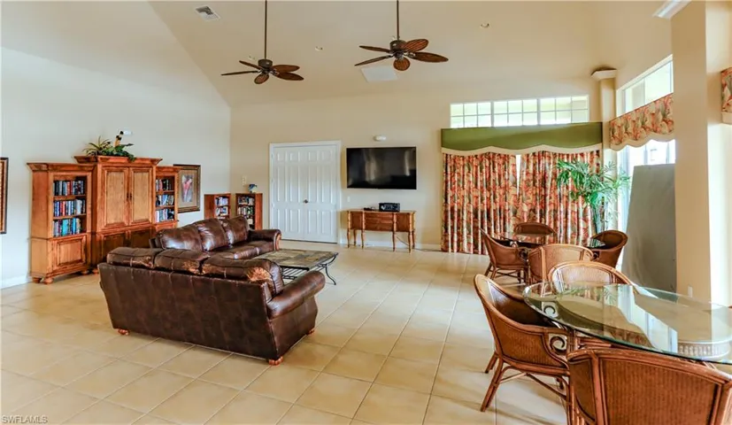 Living room with high vaulted ceiling, ceiling fan, and light tile patterned flooring