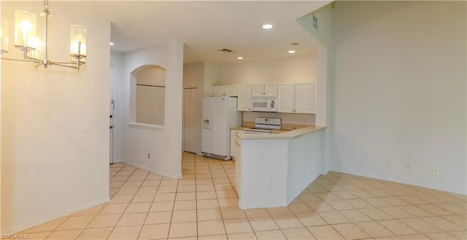 Kitchen with light countertops, recessed lighting, white appliances, a chandelier, and light tile patterned floors