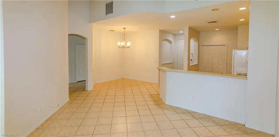 Unfurnished room with a chandelier, recessed lighting, light tile patterned floors, and arched walkways