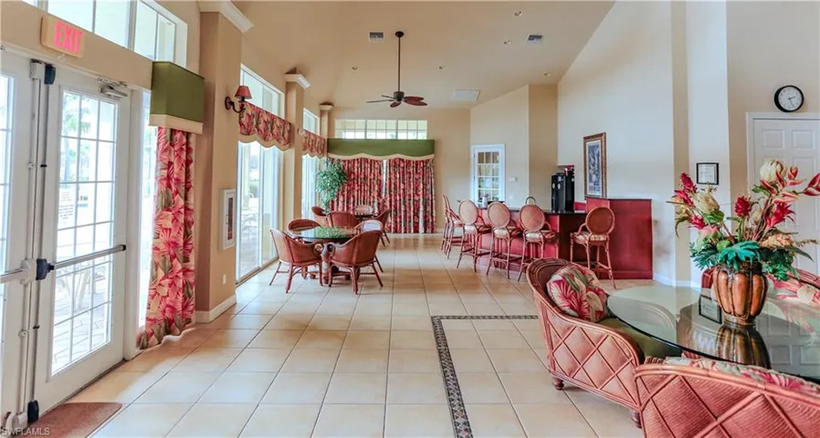 Dining room with light tile patterned floors, a towering ceiling, ceiling fan, plenty of natural light, and inlaid floor details