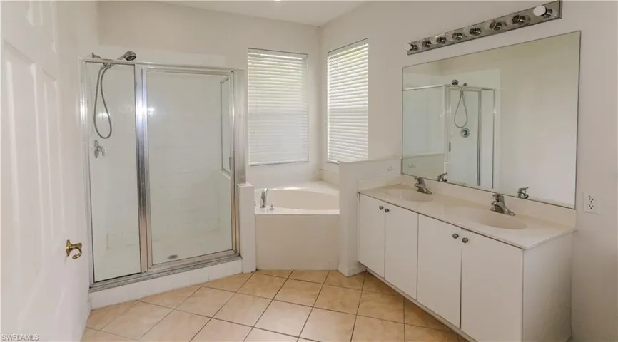 Bathroom with a stall shower, light tile patterned flooring, and a garden tub