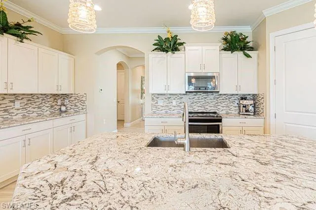Kitchen featuring tasteful backsplash, hanging light fixtures, ornamental molding, and stainless steel appliances
