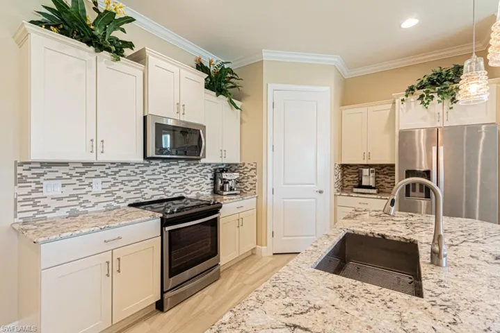 Kitchen with stainless steel appliances, decorative light fixtures, decorative backsplash, ornamental molding, and sink