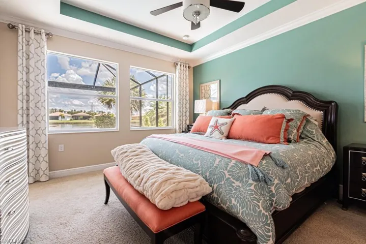 Bedroom featuring carpet floors, ceiling fan, and a raised ceiling