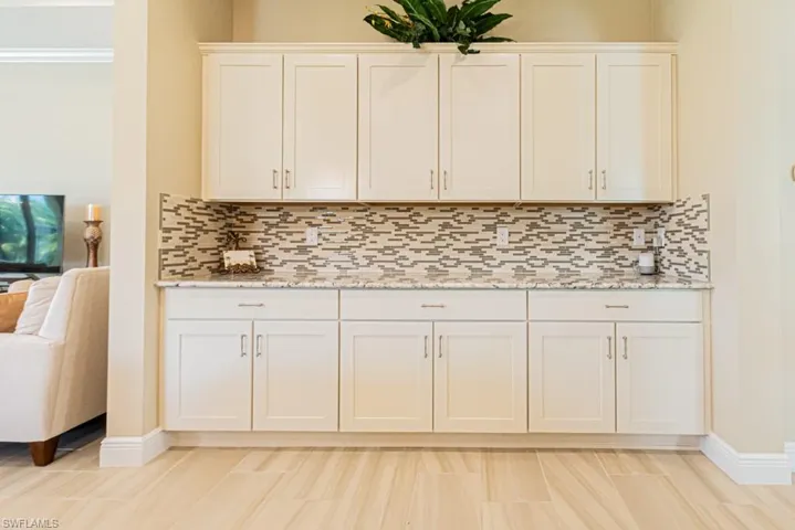 Kitchen featuring appliances with stainless steel finishes, crown molding, light stone countertops, and tasteful backsplash