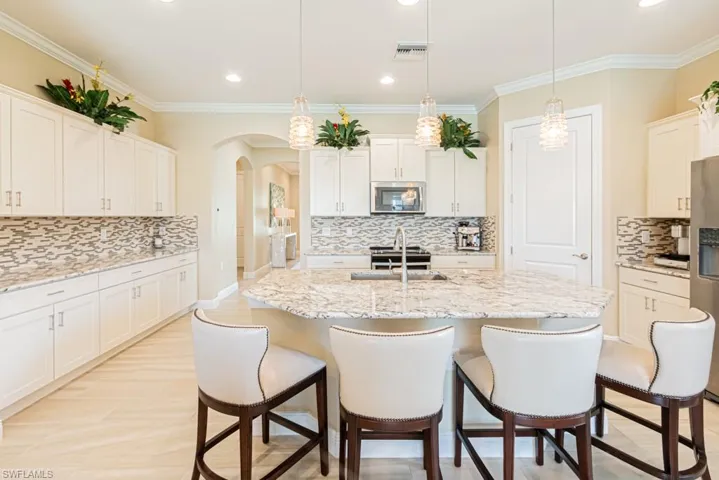 Kitchen featuring backsplash, ornamental molding, sink, decorative light fixtures, and stainless steel appliances