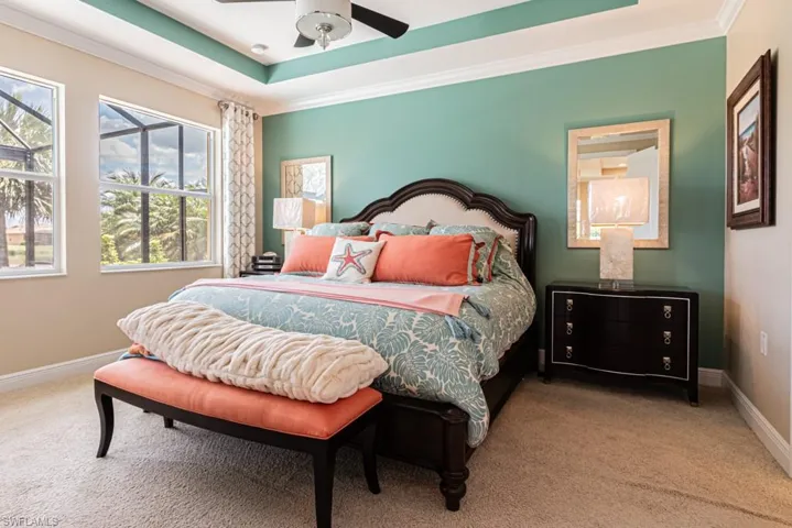 Bedroom with ceiling fan, crown molding, a tray ceiling, and carpet flooring
