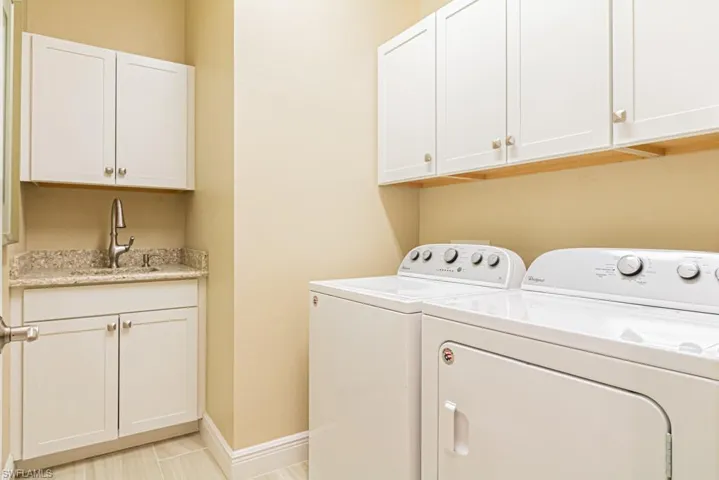 Washroom with sink, cabinets, independent washer and dryer, and light tile patterned floors