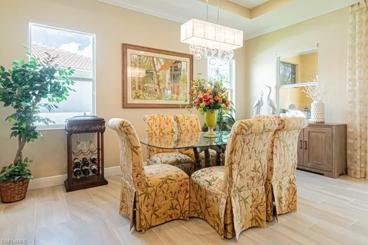 Tiled dining space with crown molding and a chandelier
