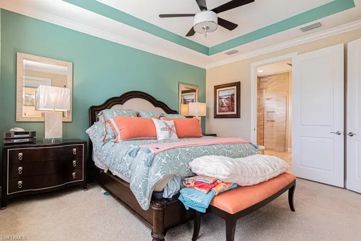 Bedroom featuring ornamental molding, connected bathroom, ceiling fan, a raised ceiling, and light colored carpet