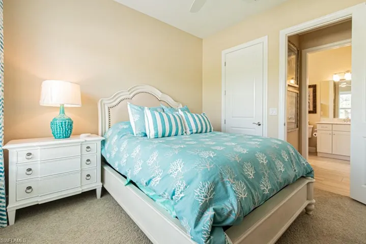 Bedroom featuring ensuite bath, ceiling fan, and light carpet