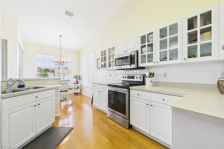Kitchen with white cabinets, stainless steel appliances, pendant lighting, and tasteful backsplash