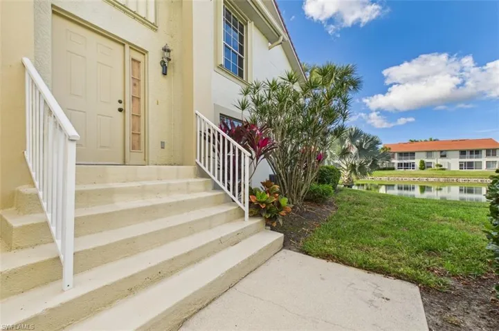 Entrance to property featuring a water view, a yard, and stucco siding