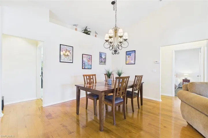 Dining space with high vaulted ceiling, light wood-type flooring, and a chandelier