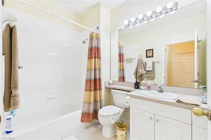 Full bath featuring shower / bath combo, vanity, and light tile patterned floors