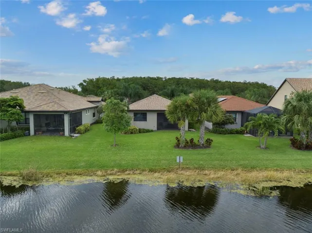 Rear view of property with a water view and a yard