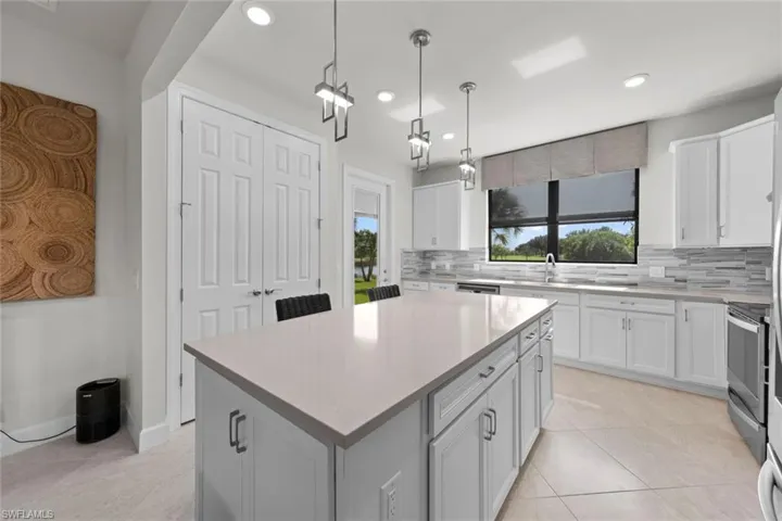 Kitchen featuring white cabinets, decorative backsplash, electric range, and a center island