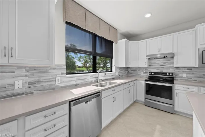 Kitchen with white cabinets, appliances with stainless steel finishes, tasteful backsplash, and sink