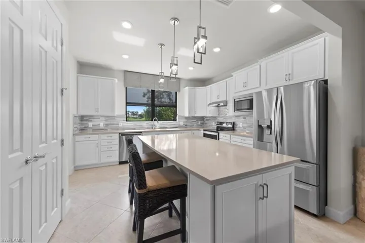 Kitchen featuring a kitchen bar, stainless steel appliances, white cabinetry, and a kitchen island