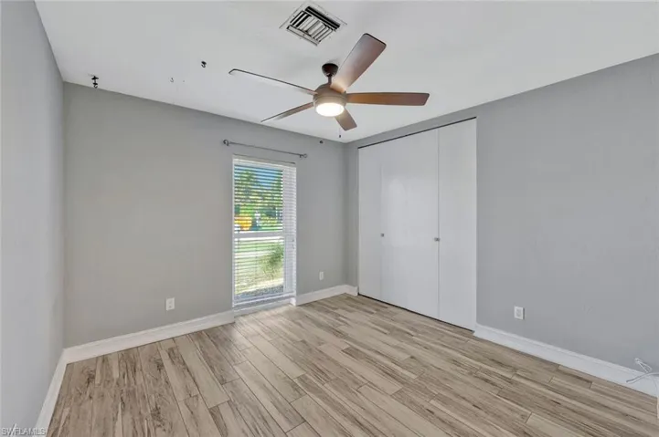Unfurnished bedroom featuring light wood-style floors, baseboards, visible vents, and a closet