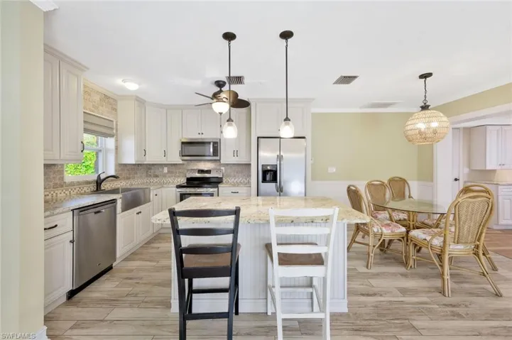 Kitchen featuring a sink, visible vents, appliances with stainless steel finishes, a kitchen island, and ornamental molding