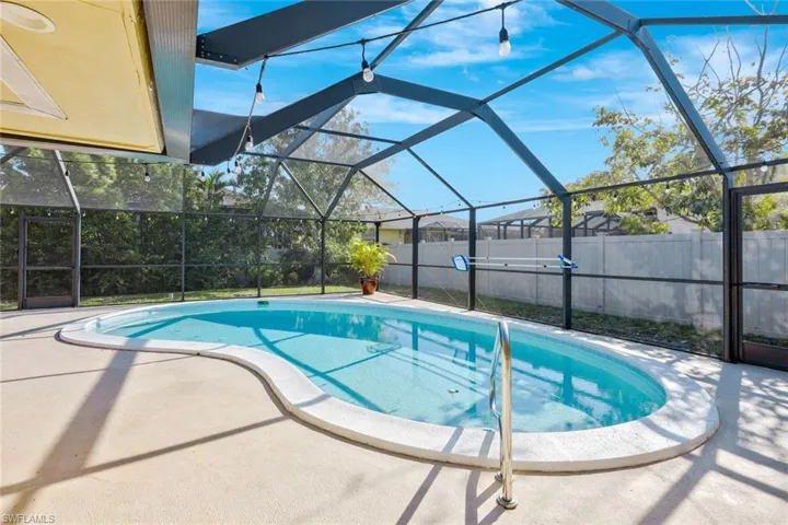 View of swimming pool featuring glass enclosure, a fenced in pool, a patio area, and fence