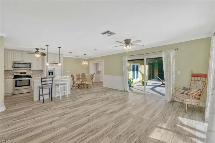 Living room with light wood finished floors, a ceiling fan, and visible vents