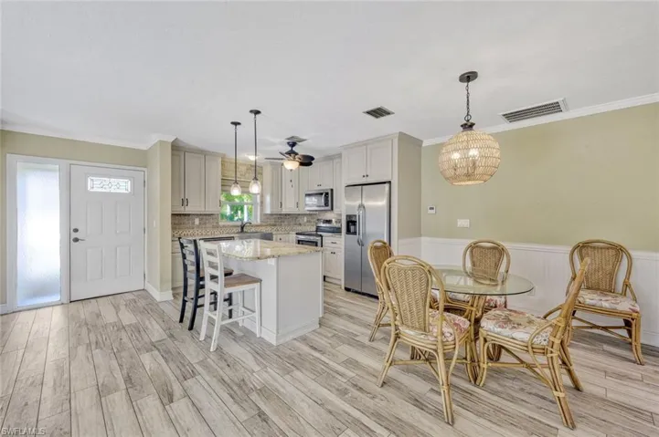 Dining room with wainscoting, light wood-style floors, and visible vents