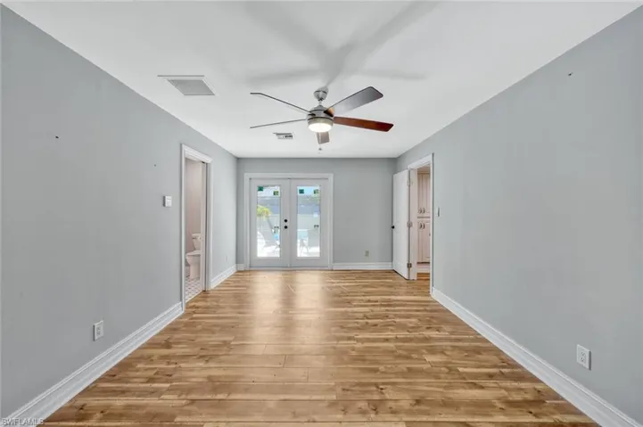 Empty room featuring visible vents, french doors, baseboards, light wood-style flooring, and ceiling fan