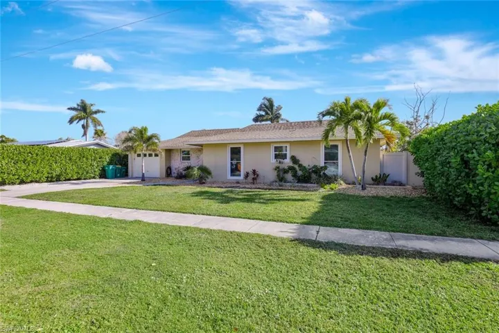 Ranch-style home with concrete driveway, fence, an attached garage, a front yard, and stucco siding