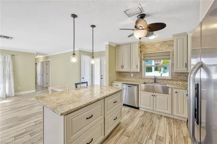 Kitchen featuring visible vents, appliances with stainless steel finishes, cream cabinets, and a sink
