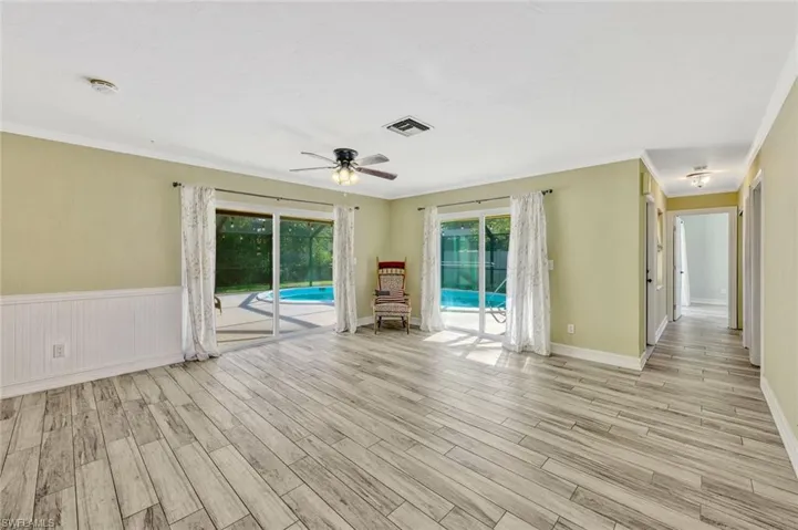 Unfurnished room featuring a ceiling fan, visible vents, ornamental molding, and light wood-style flooring