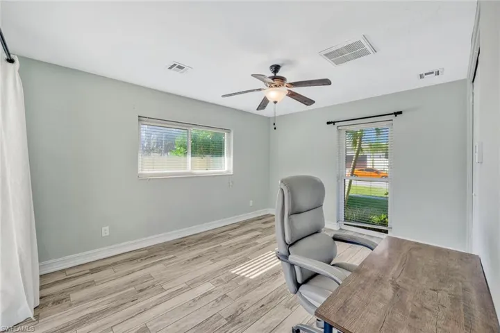 Office area featuring a ceiling fan, visible vents, and light wood-style flooring