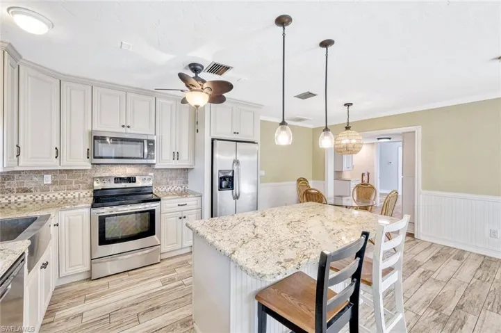 Kitchen with light wood finished floors, a ceiling fan, visible vents, and appliances with stainless steel finishes