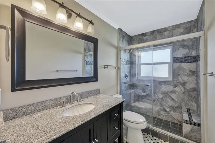 Full bathroom with vanity, a shower stall, ornamental molding, and toilet