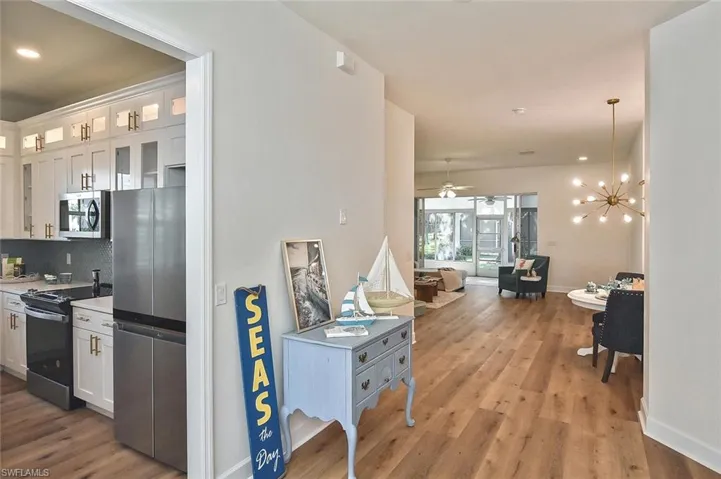 Kitchen featuring decorative backsplash, stainless steel appliances, light hardwood / wood-style floors, and white cabinets