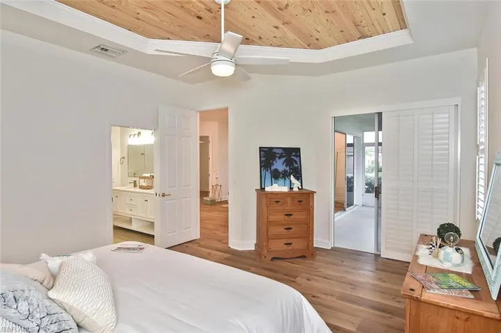 Bedroom with wooden ceiling, connected bathroom, hardwood / wood-style floors, and a raised ceiling
