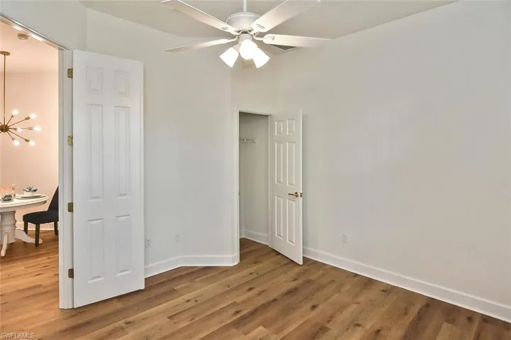 Bedroom with ceiling fan with notable chandelier and bedroom 2 hardwood / wood-style floors