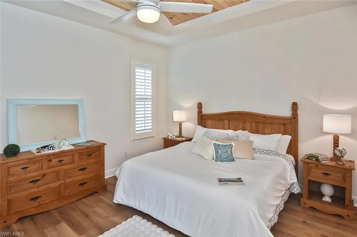Bedroom featuring ceiling fan, a raised ceiling, and light hardwood / wood-style floors