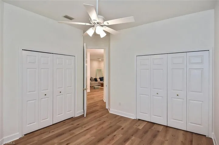 bedroom 3 featuring two closets, ceiling fan, and wood-type flooring