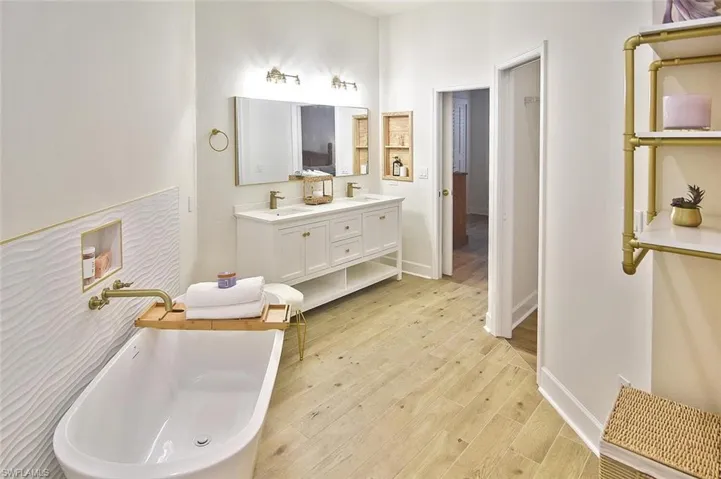 Bathroom with a washtub, wood-type flooring, and double sink vanity