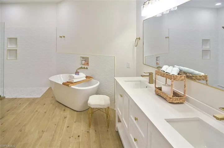 Bathroom with wood-type flooring, a bath, and double sink vanity