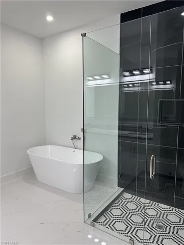 Bathroom featuring a freestanding tub, a stall shower, recessed lighting, and light marble finish floors