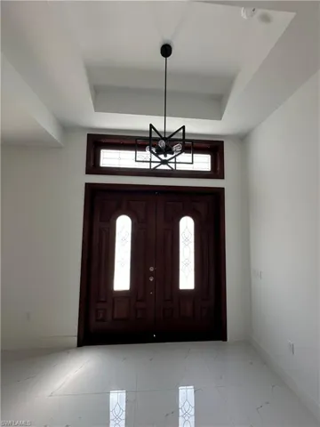 Foyer featuring a tray ceiling and light marble finish floors