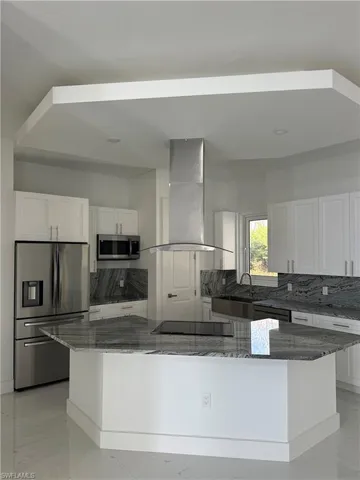 Kitchen featuring tasteful backsplash, dark stone countertops, and white cabinets