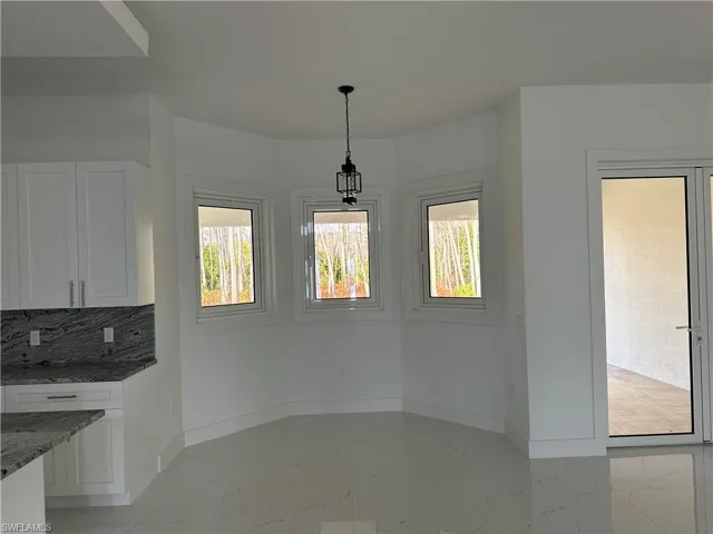 Unfurnished dining area with baseboards and light marble finish floors