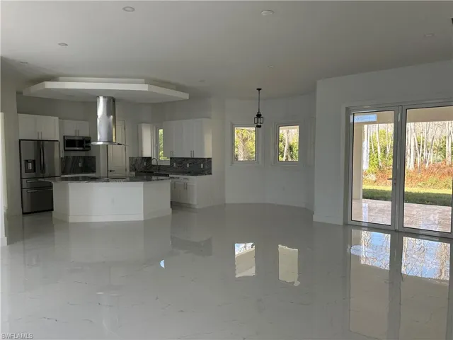 Kitchen featuring plenty of natural light, stainless steel appliances, white cabinetry, and open floor plan